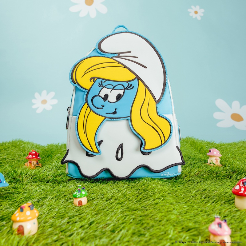 Cosplay mini backpack of Smurfette from The Smurfs sitting on green grass with a light blue background with daisies and mushroom houses. 